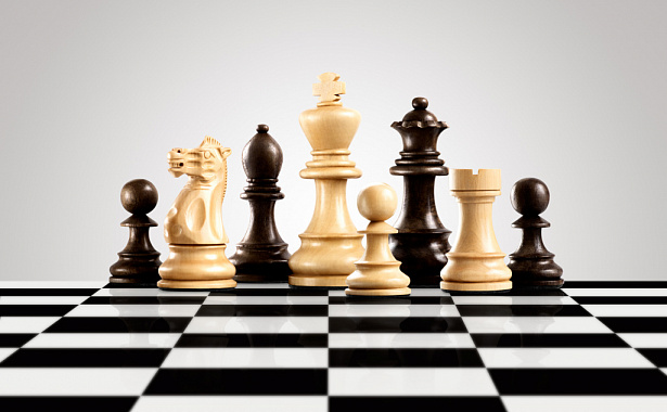на изображении шахматные фигуры в два ряда на чёрно-белом поле