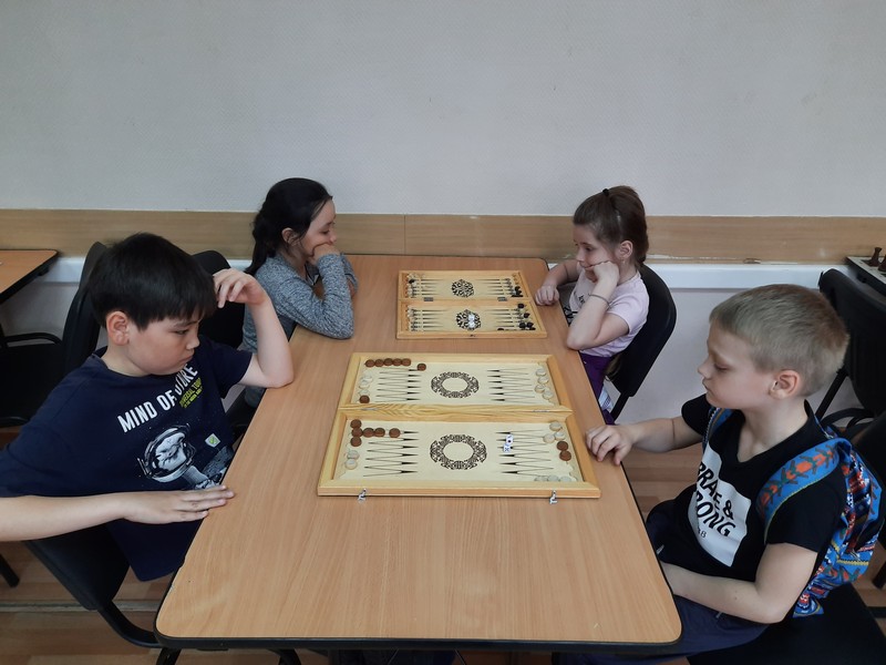 на фотографии дети играют в нарды, в шахматно-шашечном клубе «Белая ладья»