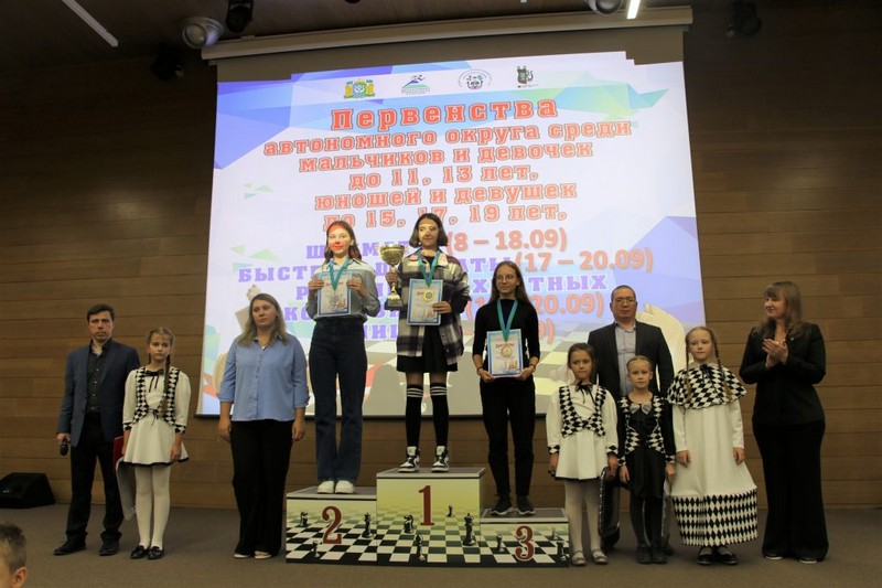 на фотографии победители и призеры первенства округа по шахматам стоят с дипломами и медалями на пьедестале